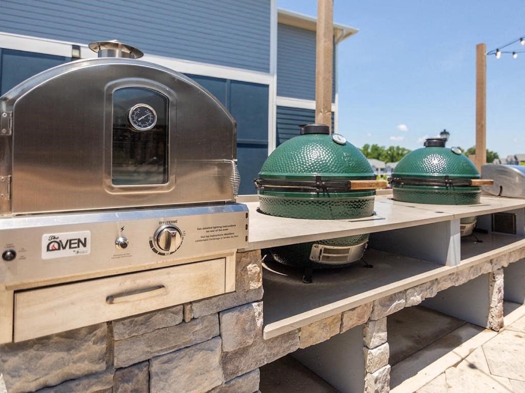 a grill and two pots and pans on a picnic table in front of a house