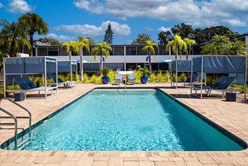 a swimming pool with chairs and a building in the background