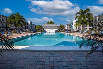 a large swimming pool with palm trees next to a building