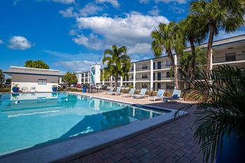 a swimming pool with palm trees next to a hotel