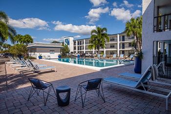 a swimming pool with chairs and tables in front of a building