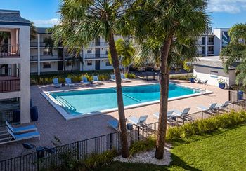 a swimming pool with palm trees in front of an apartment building