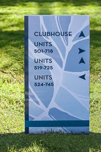 a sign for a clubhouse is in the grass
