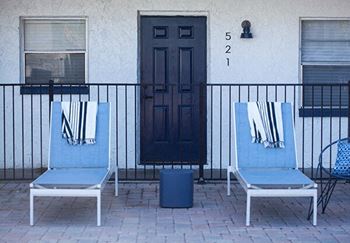 two blue chairs on a patio in front of a door