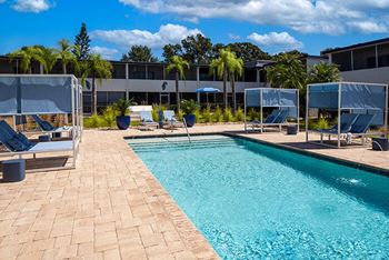 a swimming pool with chairs and umbrellas next to a building