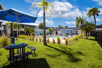 a backyard with a pool and tables and palm trees