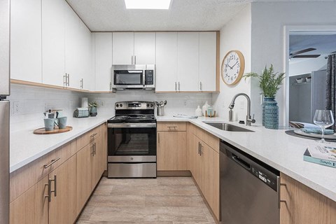 A kitchen with wooden cabinets and a stainless steel dishwasher.