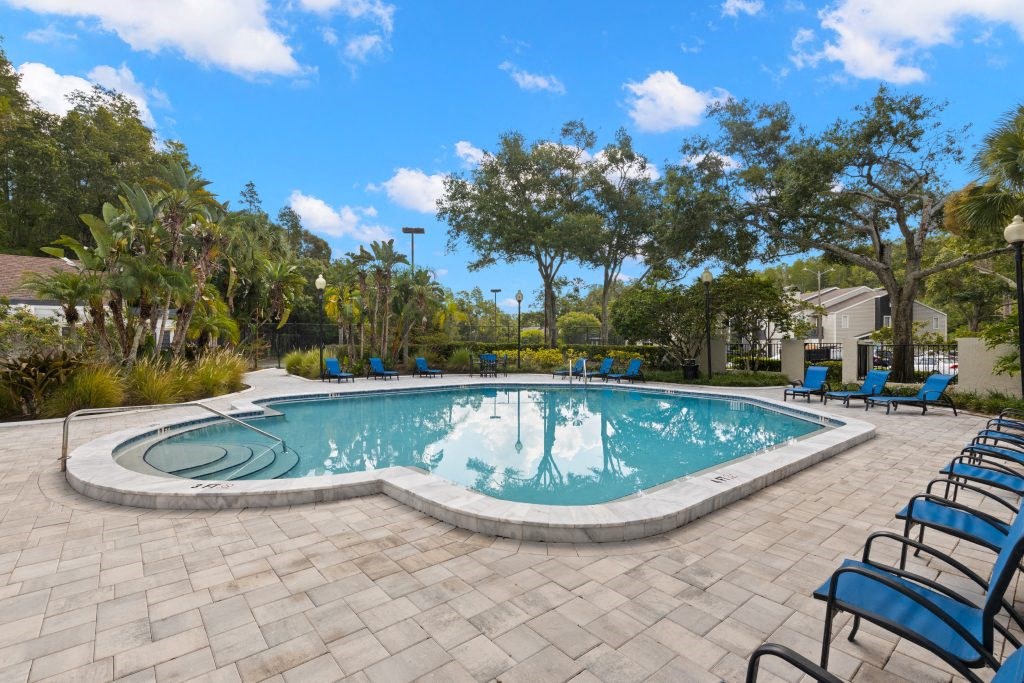 a swimming pool with blue chairs around it