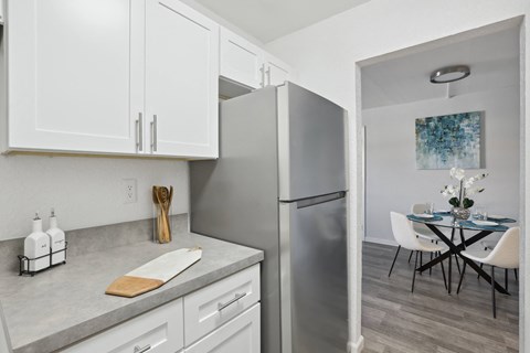 a kitchen with white cabinets and stainless steel appliances and a dining room with a table