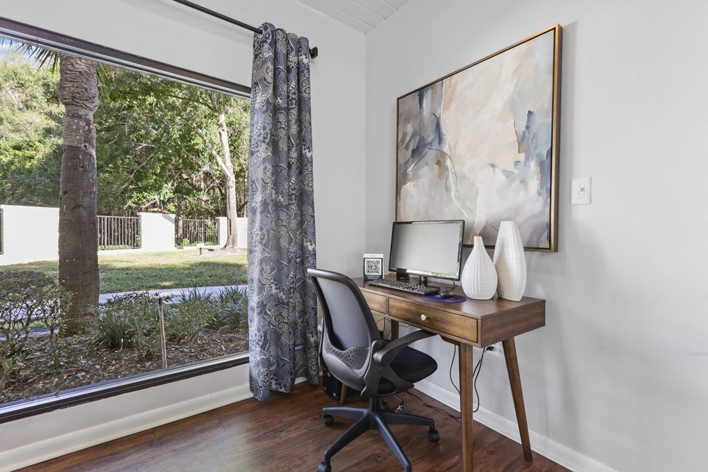 a home office with a large window and a desk with a computer
