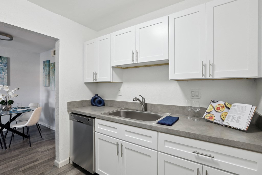a kitchen with white cabinets and a stainless steel sink   and a dining room