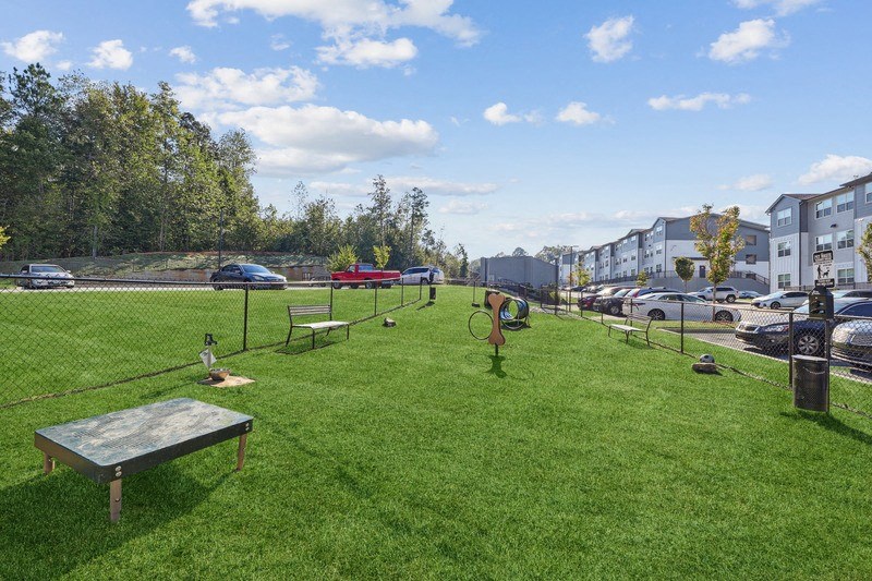 a park with a tennis court and benches in the grass