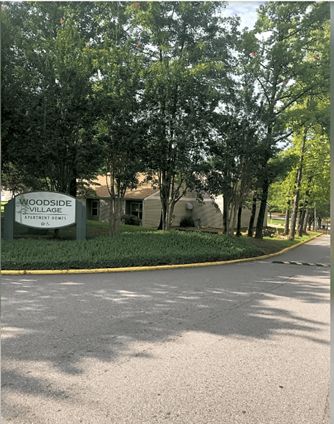 a sign on the side of a road in front of a house
