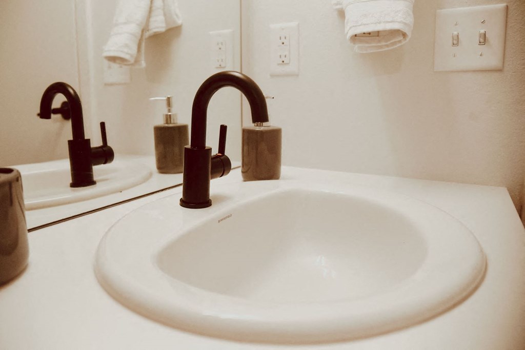 a white sink with a brown faucet in a bathroom