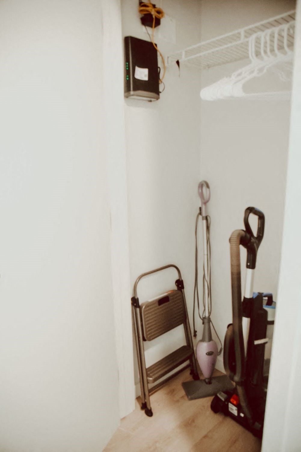 the corner of a room with a vacuum cleaner and a chair