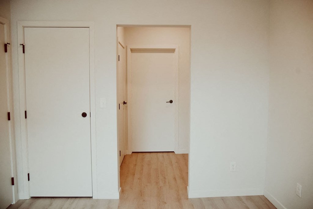 an empty room with white doors and a wooden floor