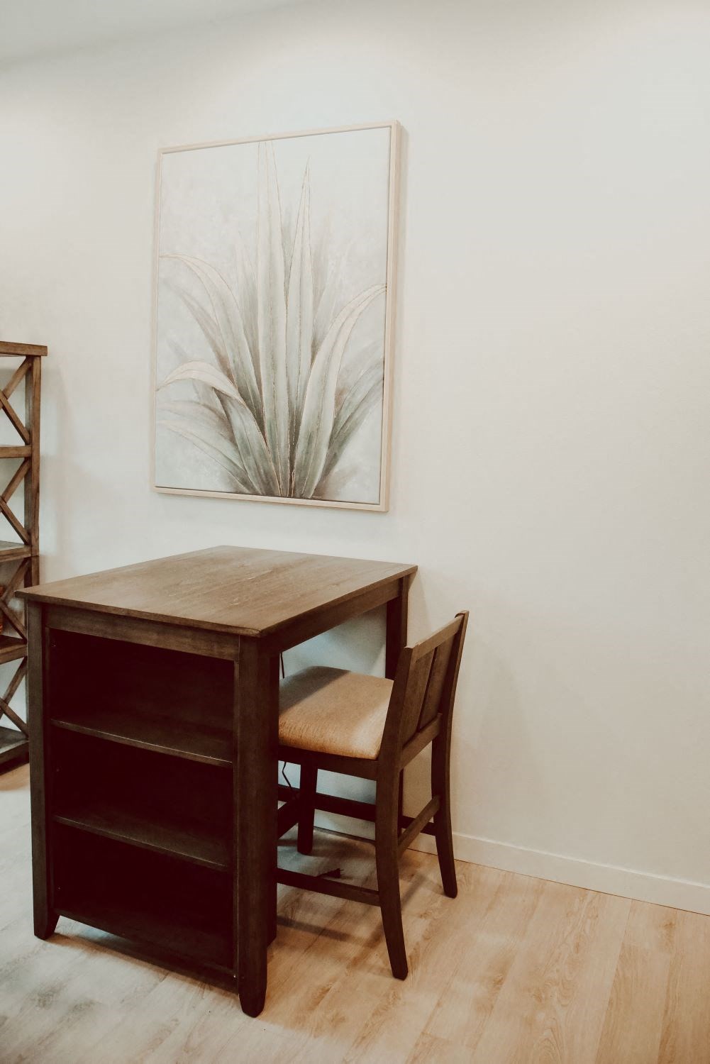 a desk and chair in a room with a picture of a plant