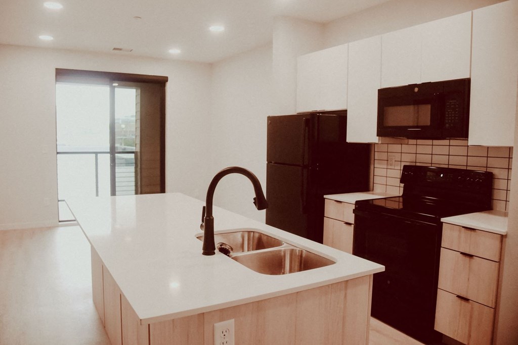 an empty kitchen with a sink in the middle of it