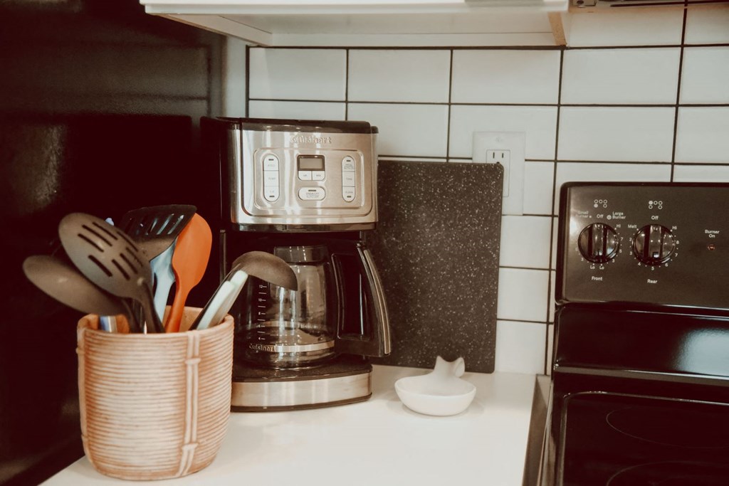 a kitchen counter with a coffee maker and utensils on it