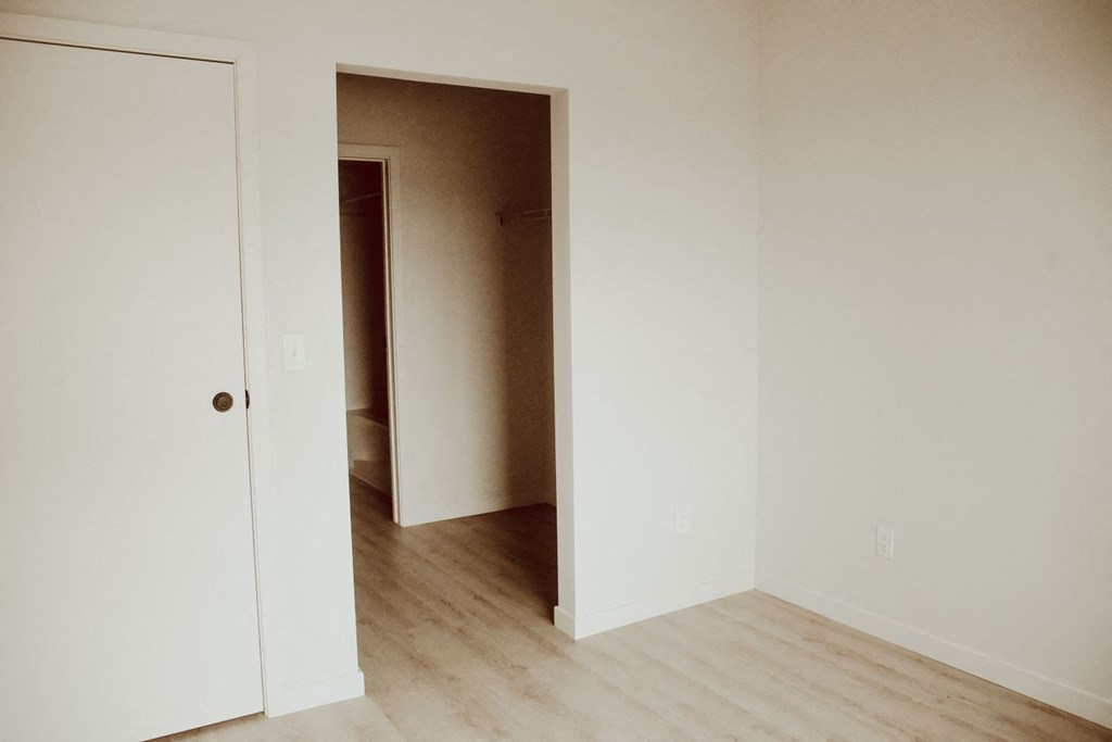 a bedroom with a door to a closet and a wood floor