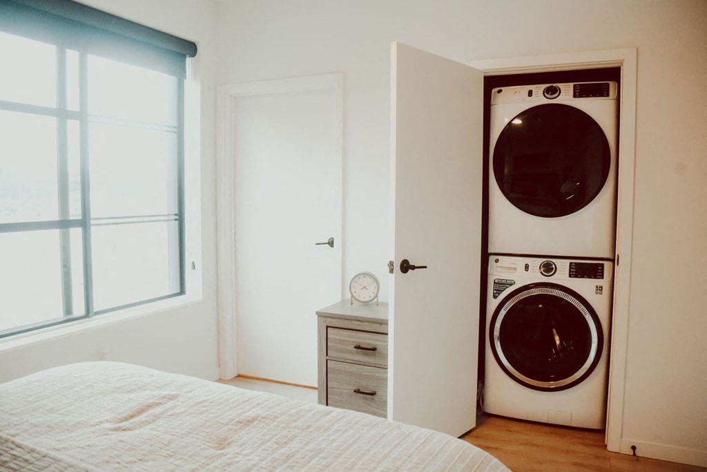 a bedroom with a bed and a washing machine in it