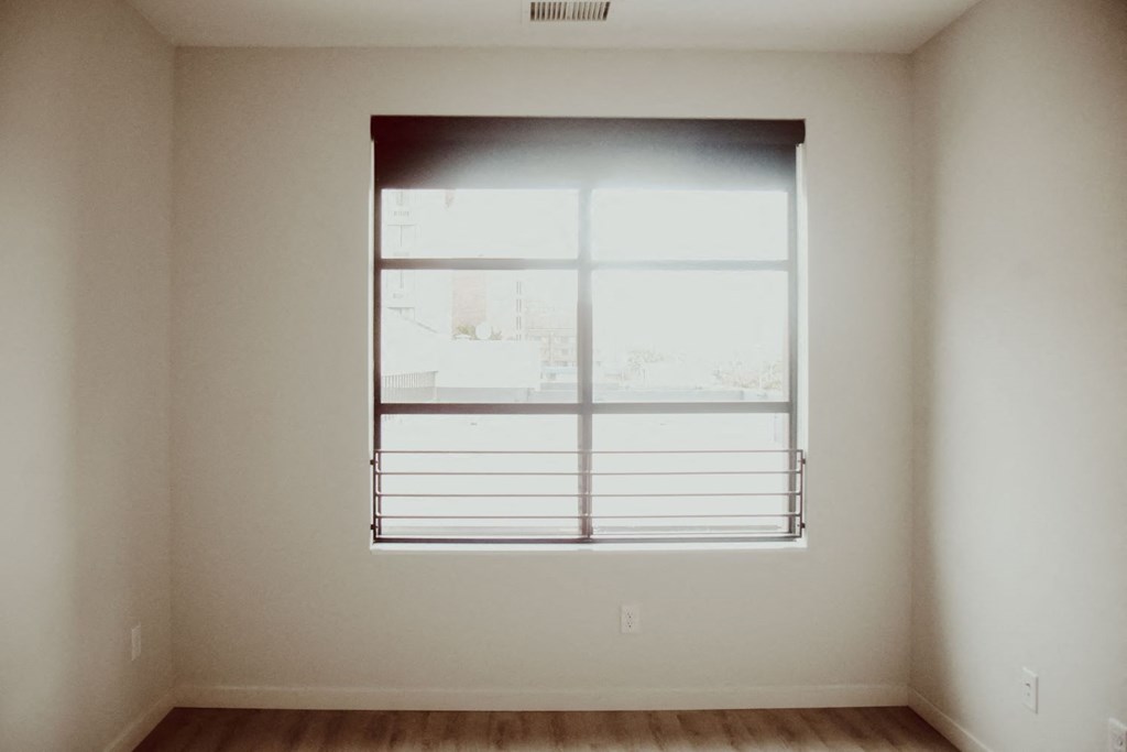 a bedroom with a large window and a wood floor