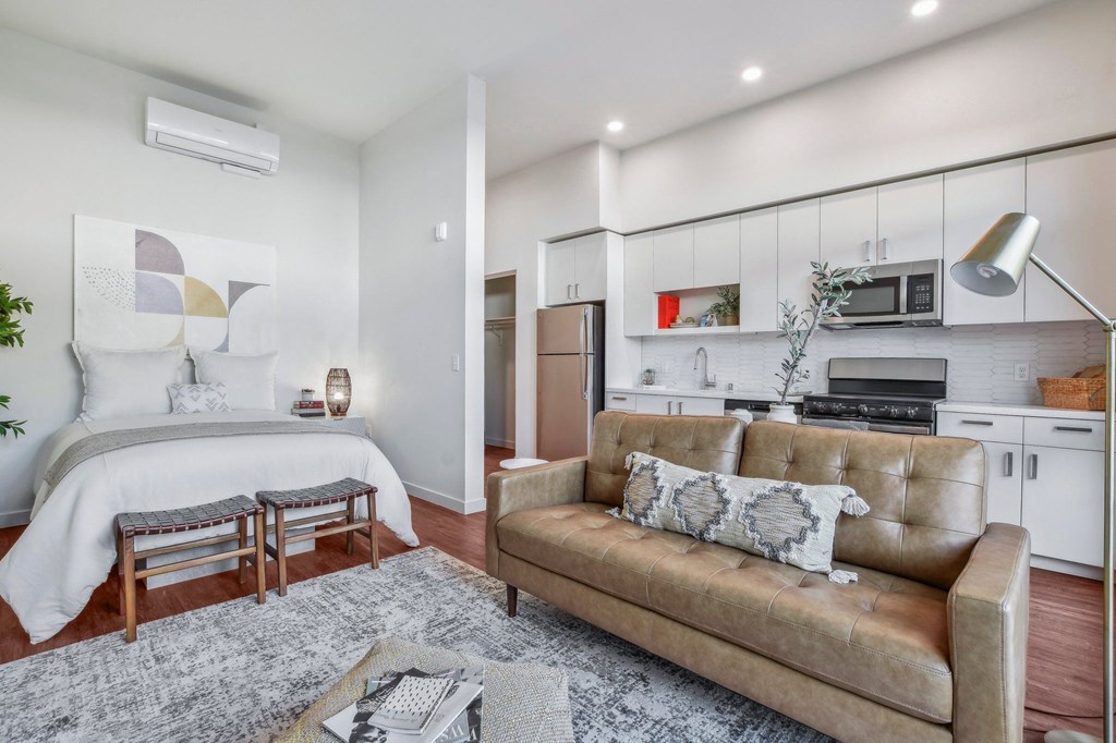 A modern living room with a brown leather couch and a grey rug.
