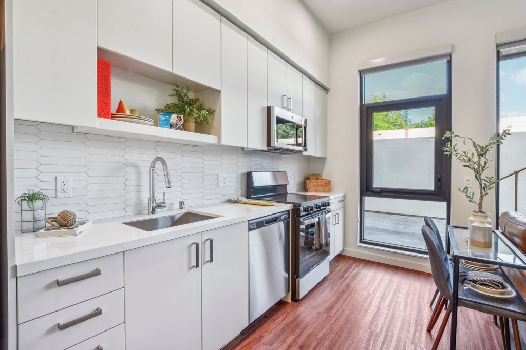 A kitchen with white cabinets and a wooden floor.