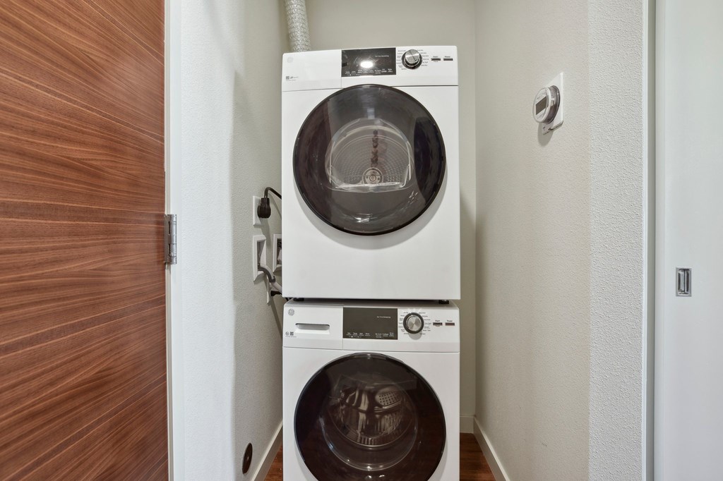 A white washing machine is on top of a white dryer in a small laundry room.