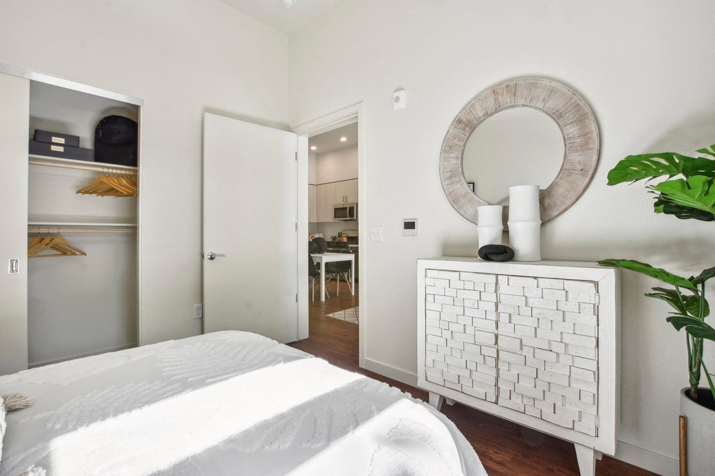 A white bedroom with a large bed and a mirror on the wall.