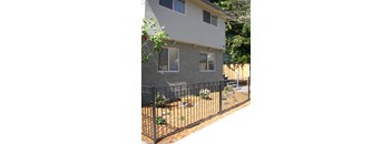 a gray brick house with a black fence