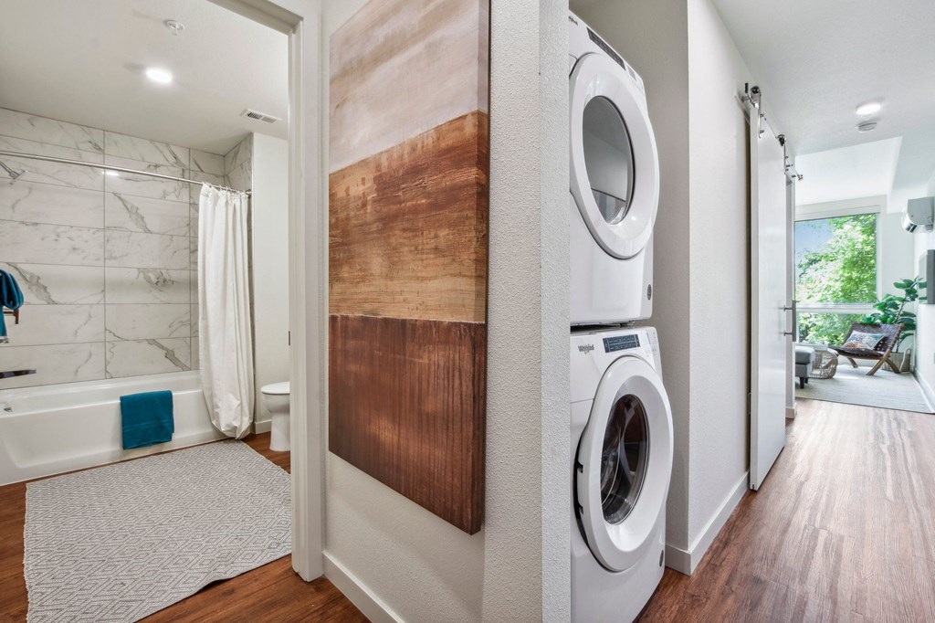 A modern bathroom with a washer and dryer built into the wall.