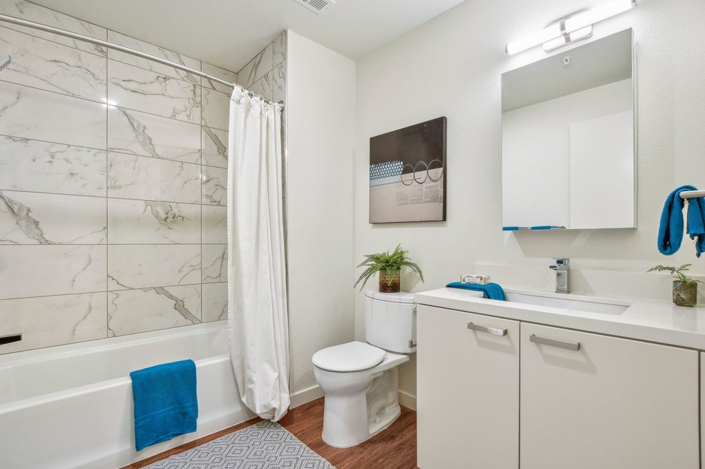 A bathroom with a white toilet, a white sink, and a white bathtub with a blue towel.
