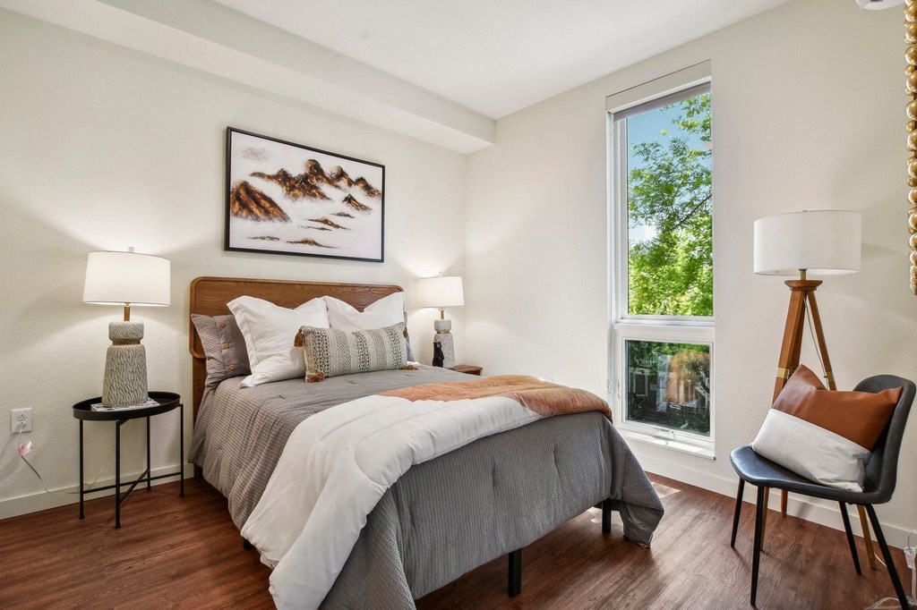 A bedroom with a large bed and a chair by the window.