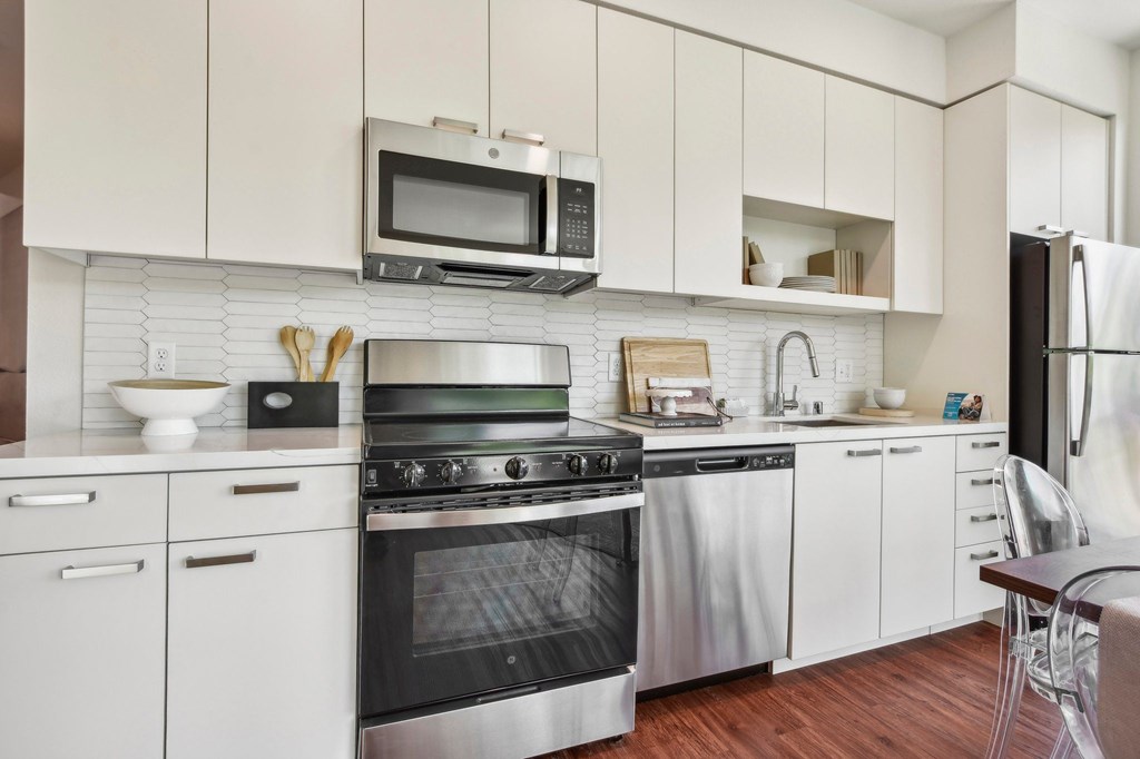 A modern kitchen with white cabinets and stainless steel appliances.