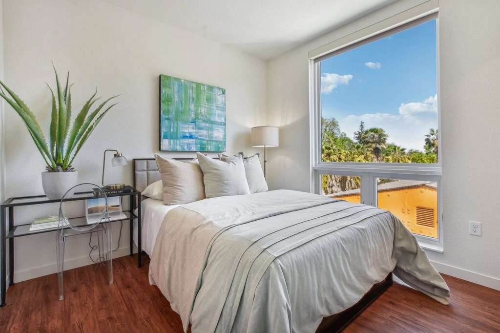A bedroom with a large bed and a view of the outdoors through a window.