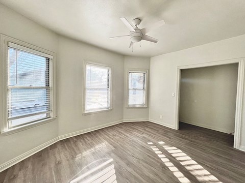 A room with a ceiling fan and wooden flooring.