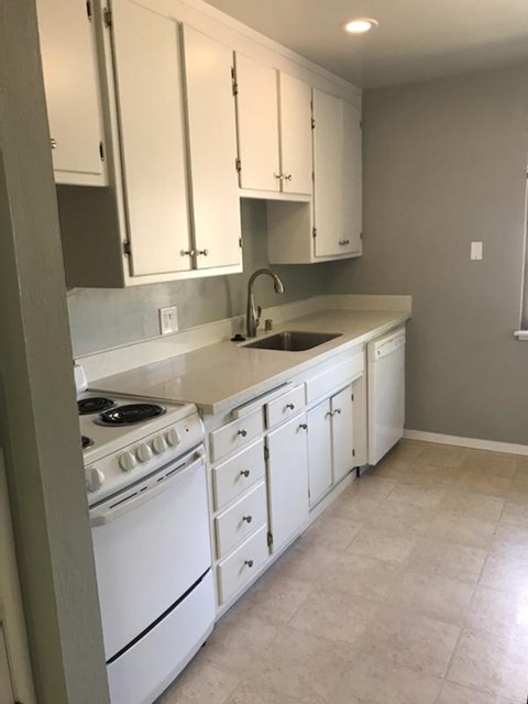 A kitchen with white cabinets and a white stove.