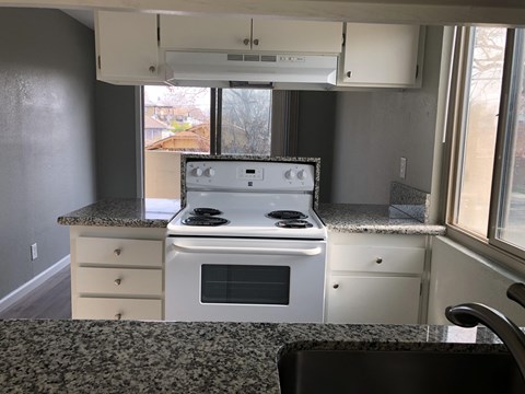 A white stove is in a kitchen with granite countertops.