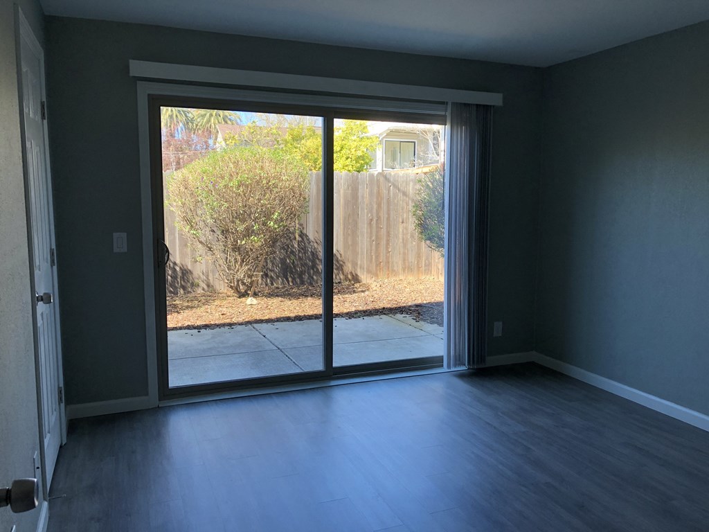 an empty living room with sliding glass doors to a backyard