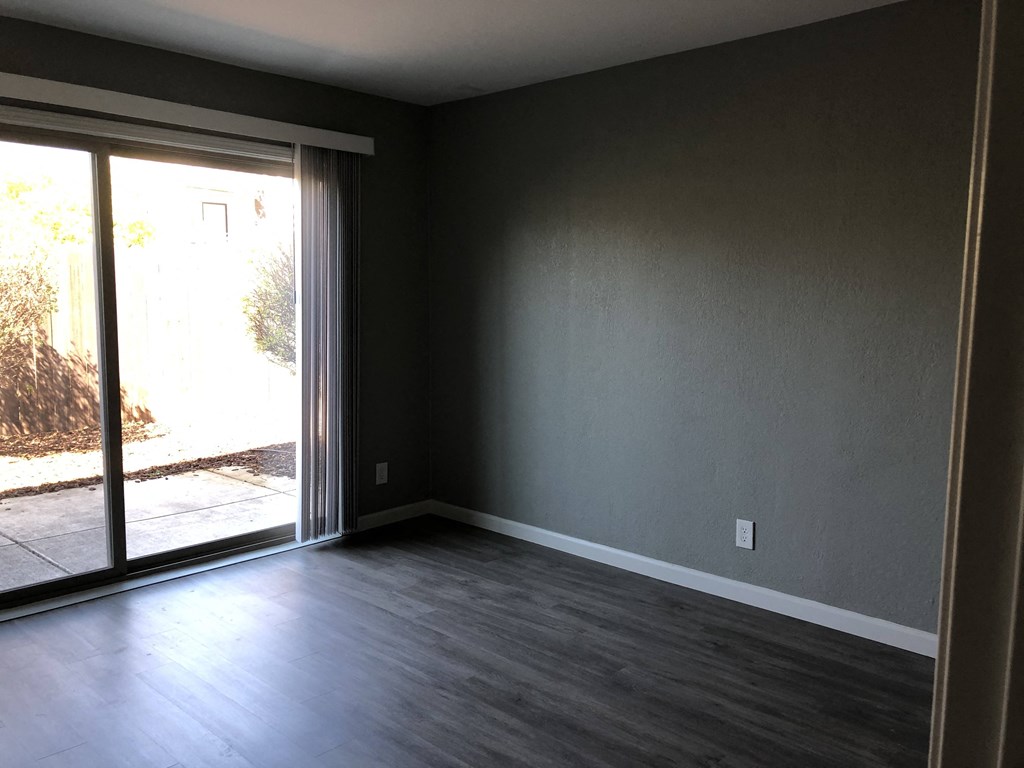 an empty living room with wood floors and a sliding glass door