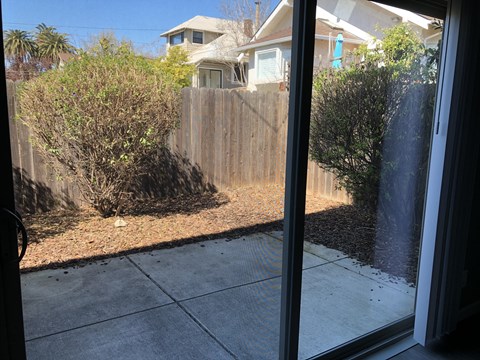 A view from inside a room looking out to a backyard with a fence and a house in the background.