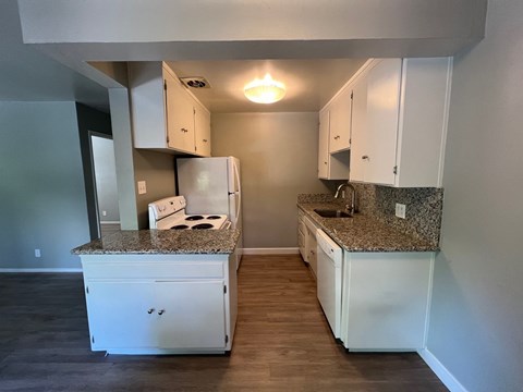 a kitchen with white cabinets and granite counter tops