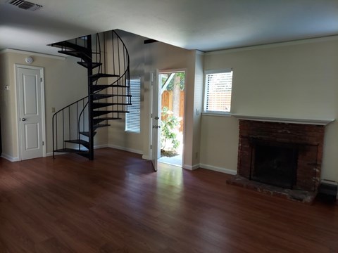 A room with a spiral staircase and a fireplace.