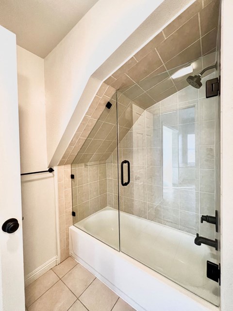 A white bathroom with a tiled shower and a white bathtub.