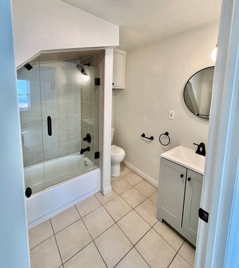 A white bathroom with a glass shower stall and a white sink.