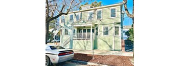 a green house with a white car parked in front of it