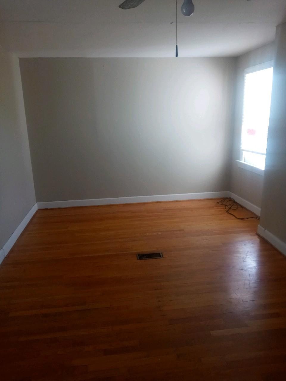 an empty room with wooden floors and a window
