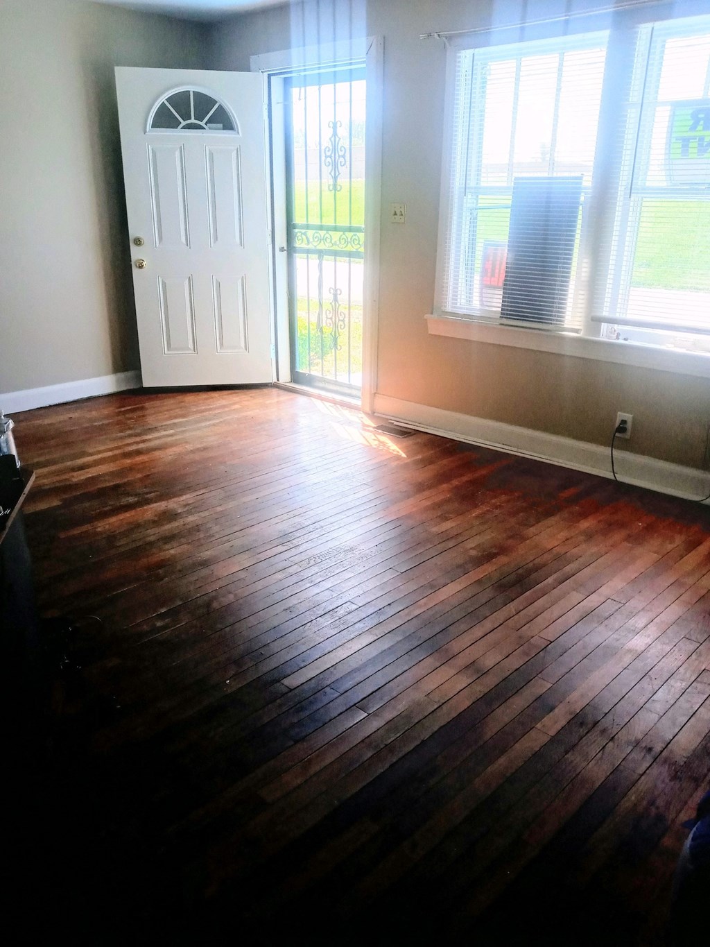 an empty living room with wooden floors and a door