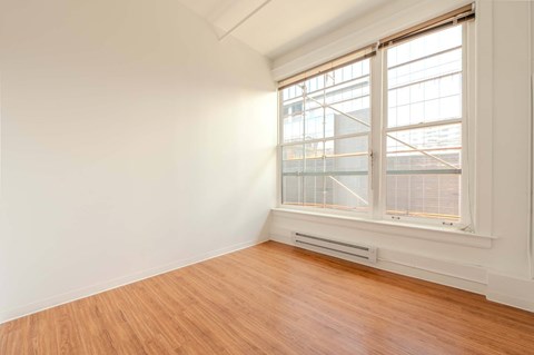 A room with a window and wooden flooring.